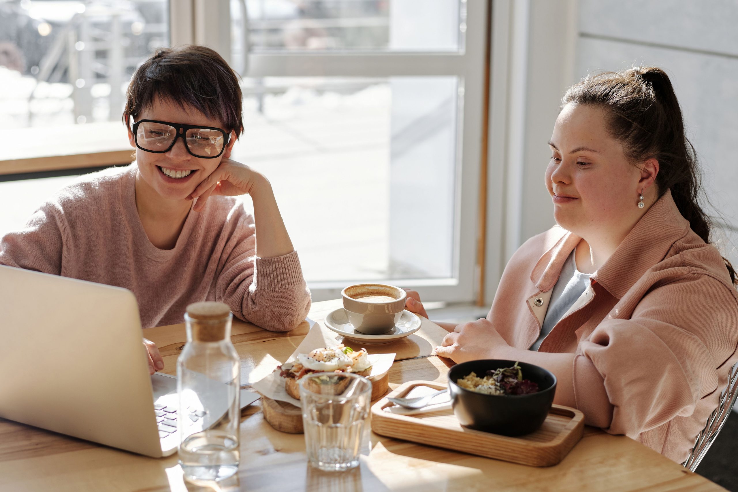 Support worker using a laptop with a young woman with Down syndrome